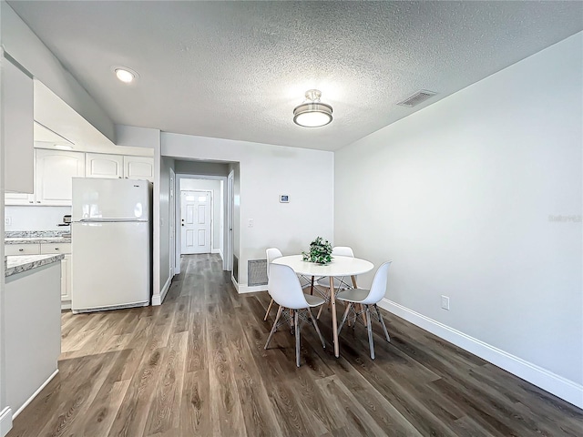 dining room featuring dark wood-type flooring and a textured ceiling