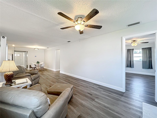 living room featuring ceiling fan, dark hardwood / wood-style floors, and a textured ceiling