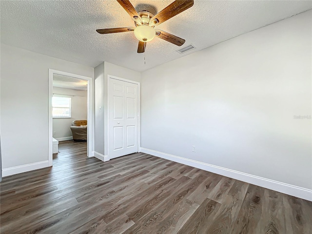 unfurnished bedroom featuring dark hardwood / wood-style floors, a textured ceiling, a closet, and ceiling fan