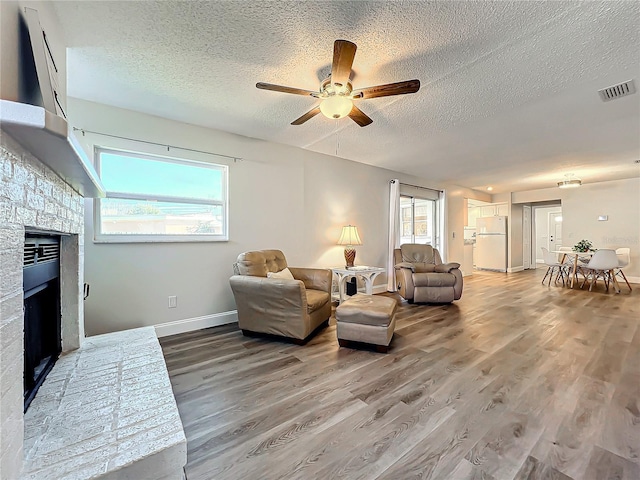 living room with wood-type flooring, ceiling fan, and a textured ceiling