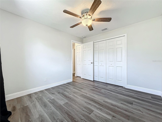 unfurnished bedroom featuring ceiling fan, wood-type flooring, a closet, and a textured ceiling