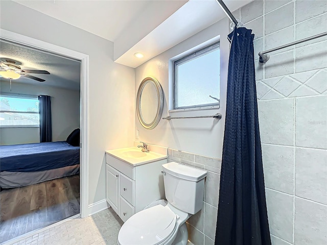 bathroom featuring vanity, ceiling fan, tile walls, and toilet