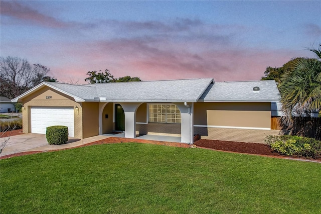 ranch-style home featuring a garage and a lawn