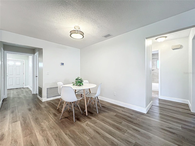 dining space featuring dark hardwood / wood-style flooring and a textured ceiling