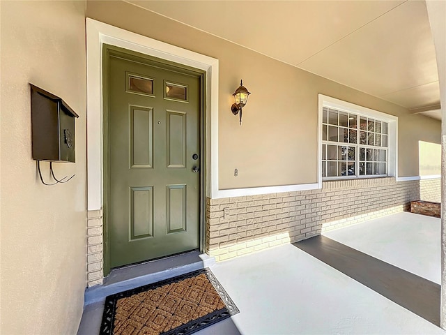 view of exterior entry featuring brick siding and stucco siding