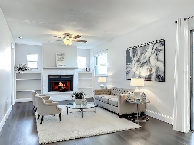 living room featuring a warm lit fireplace, wood finished floors, a ceiling fan, visible vents, and baseboards