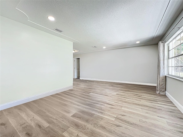 empty room with baseboards, visible vents, a textured ceiling, light wood-type flooring, and recessed lighting