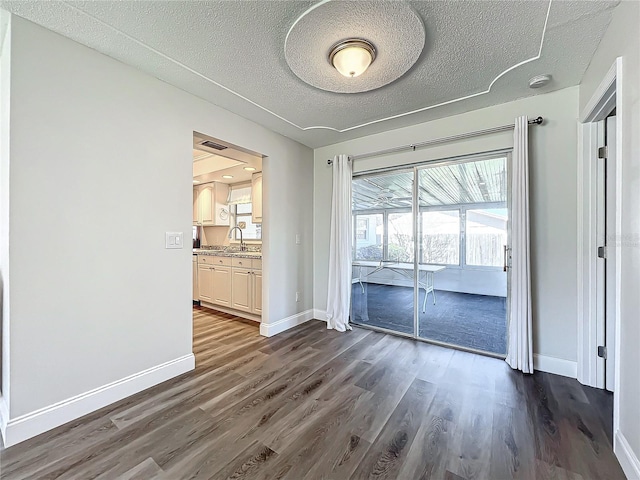 unfurnished dining area featuring dark wood-type flooring, a textured ceiling, and baseboards