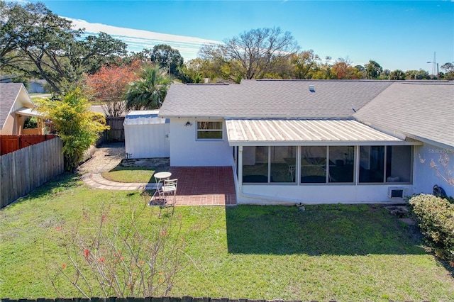 back of property featuring a sunroom, metal roof, roof with shingles, fence private yard, and a yard