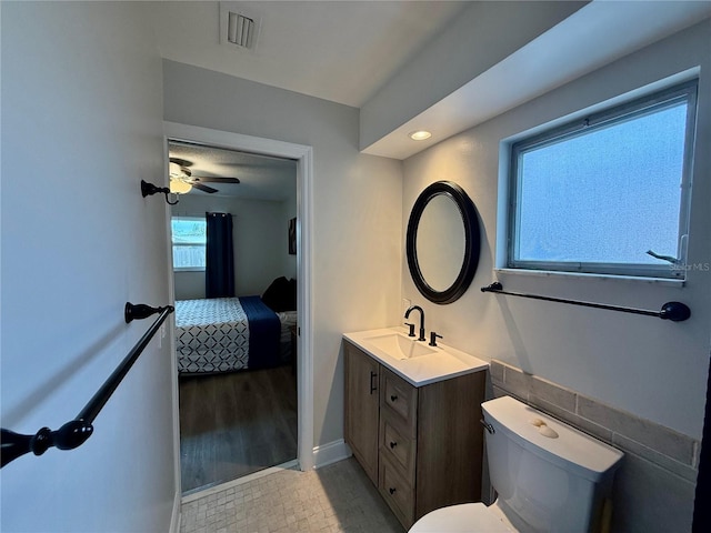 ensuite bathroom featuring toilet, vanity, visible vents, baseboards, and ensuite bath