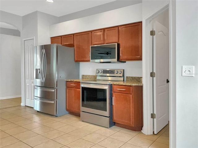 kitchen with stainless steel appliances, light stone countertops, and light tile patterned floors