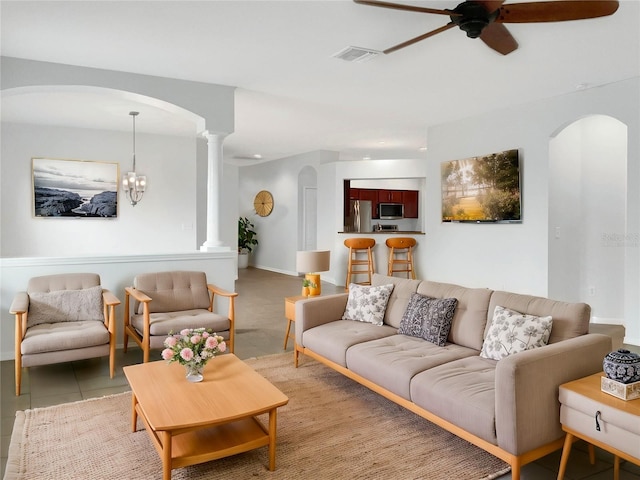 living room featuring light tile patterned floors, ceiling fan with notable chandelier, and ornate columns