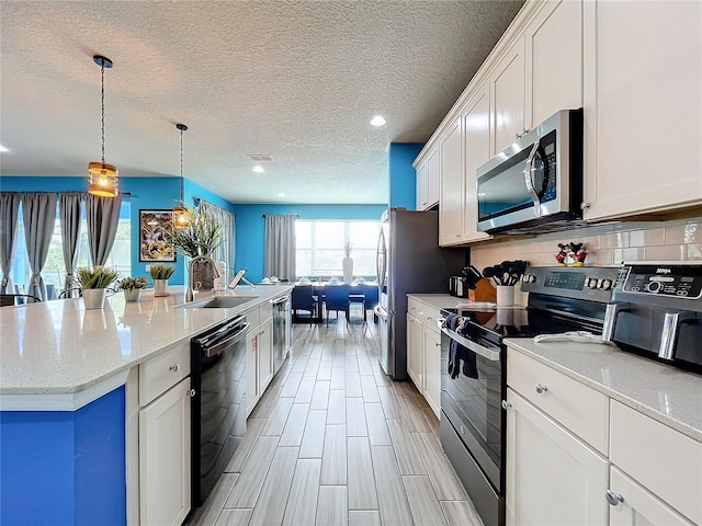 kitchen featuring sink, stainless steel appliances, white cabinetry, and a center island with sink