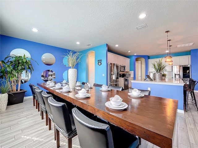 dining space featuring light wood-type flooring and a textured ceiling