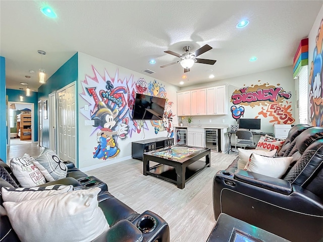 living room with ceiling fan, bar, light hardwood / wood-style flooring, and beverage cooler