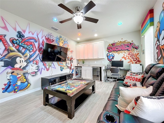 game room with light wood-type flooring, wet bar, ceiling fan, and beverage cooler