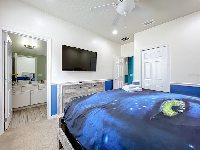 carpeted bedroom with a closet, ceiling fan, and ensuite bathroom