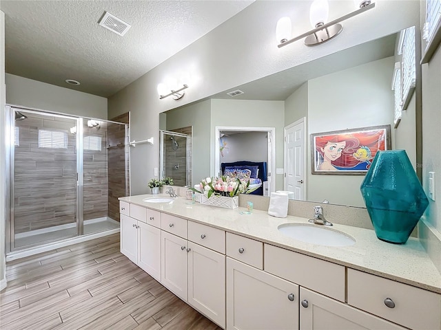 bathroom with vanity, walk in shower, and a textured ceiling