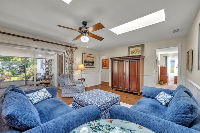 living room with plenty of natural light, light wood-type flooring, and a skylight