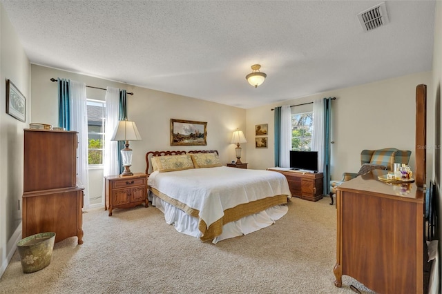 bedroom featuring multiple windows, light carpet, and a textured ceiling