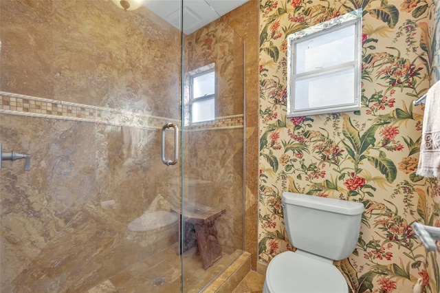 bathroom featuring a shower with shower door and toilet