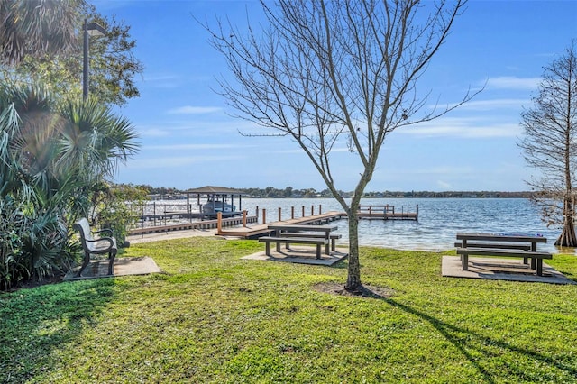 view of dock with a lawn and a water view