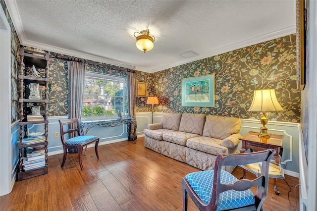 living room featuring wood-type flooring, ornamental molding, and a textured ceiling