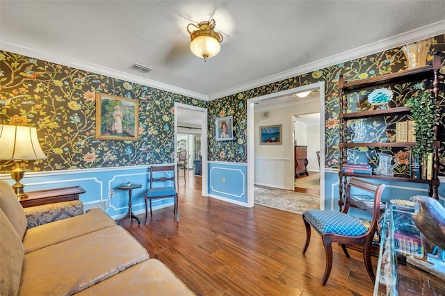 living room featuring ornamental molding, wood-type flooring, and a textured ceiling