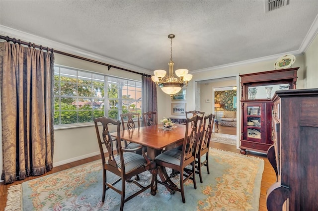 dining space with ornamental molding, an inviting chandelier, a textured ceiling, and light hardwood / wood-style flooring