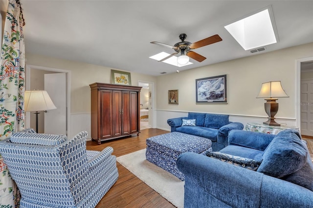 living room featuring hardwood / wood-style floors, ceiling fan, and a skylight