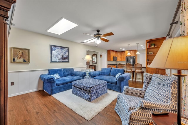 living room with wood-type flooring, ceiling fan, and a skylight