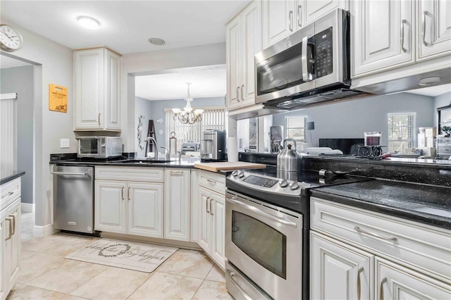 kitchen with sink, light tile patterned flooring, white cabinets, and appliances with stainless steel finishes