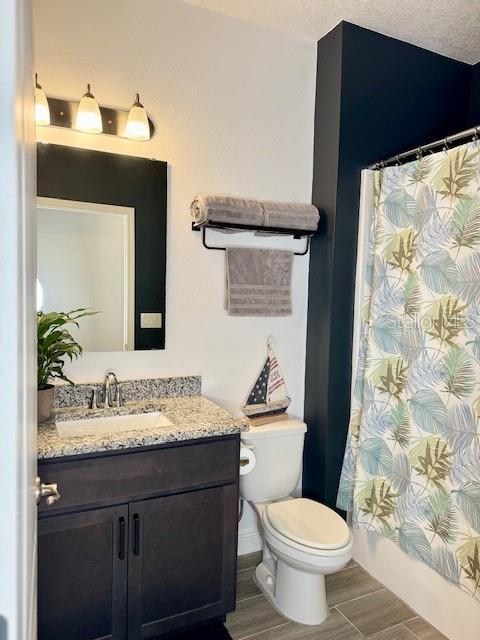 bathroom featuring vanity, toilet, a shower with shower curtain, and a textured ceiling