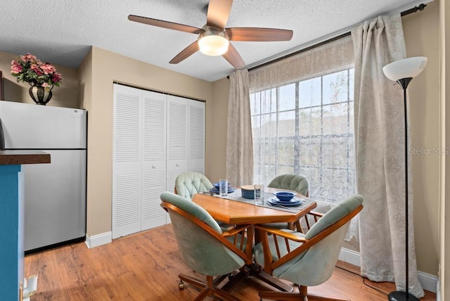 dining area featuring ceiling fan, a textured ceiling, and light wood-type flooring