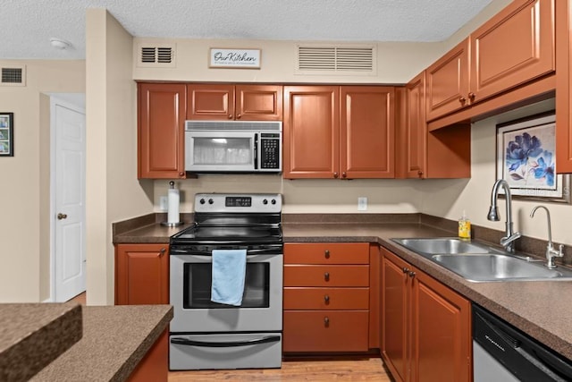 kitchen with sink, stainless steel appliances, light hardwood / wood-style floors, and a textured ceiling