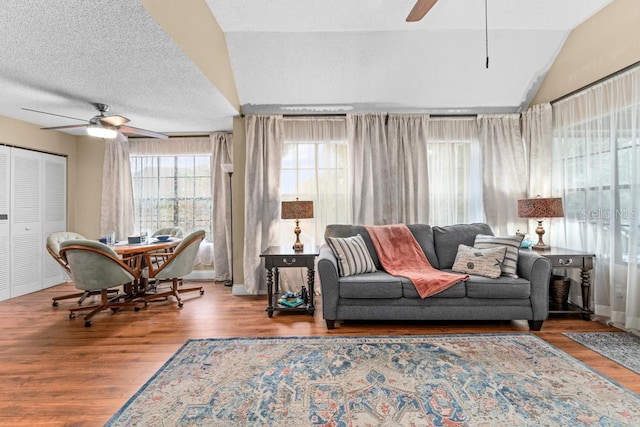 living room featuring lofted ceiling, hardwood / wood-style floors, a textured ceiling, and ceiling fan