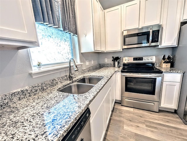 kitchen featuring light hardwood / wood-style floors, appliances with stainless steel finishes, sink, white cabinets, and light stone counters