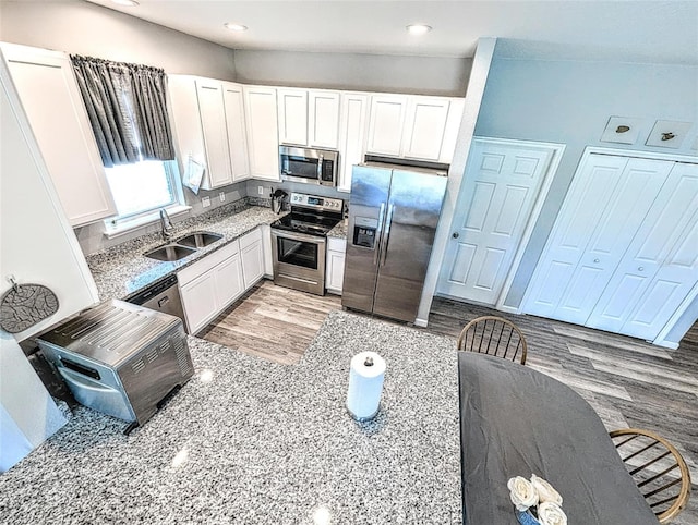 kitchen featuring sink, white cabinets, stainless steel appliances, and light wood-type flooring