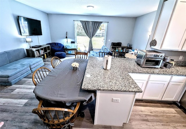 kitchen featuring white cabinetry, light stone counters, light hardwood / wood-style flooring, and a breakfast bar