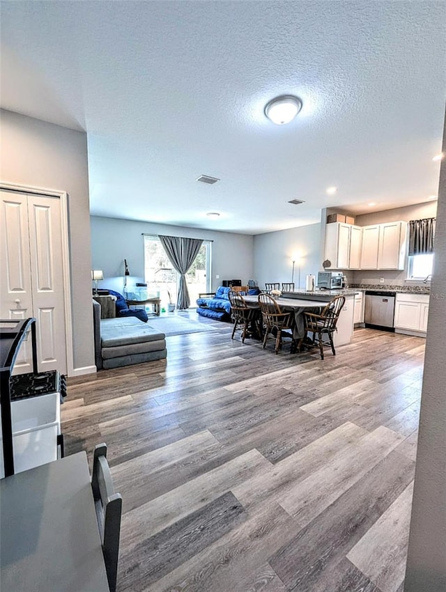 dining space with a textured ceiling and light hardwood / wood-style flooring