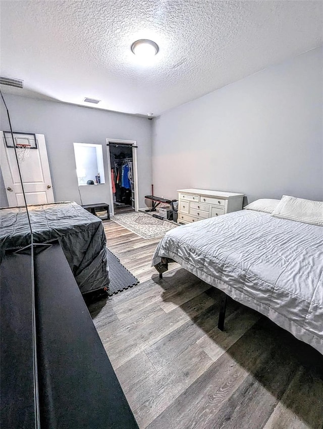 bedroom with a textured ceiling, a closet, and light hardwood / wood-style flooring