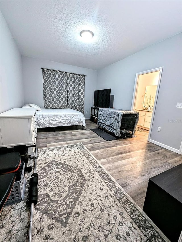 bedroom featuring hardwood / wood-style flooring, a textured ceiling, and ensuite bath