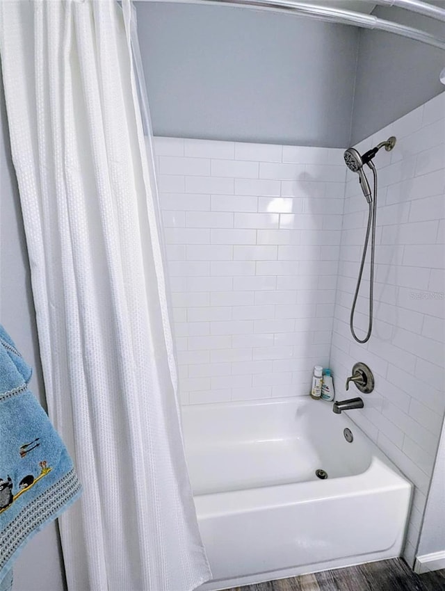 bathroom featuring wood-type flooring and shower / bathtub combination with curtain