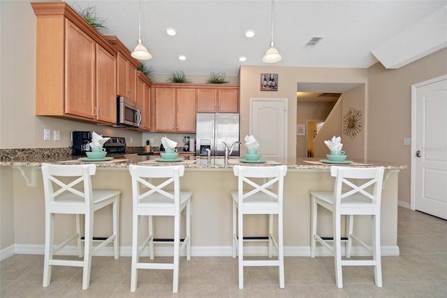 kitchen with stainless steel appliances, pendant lighting, and a kitchen breakfast bar