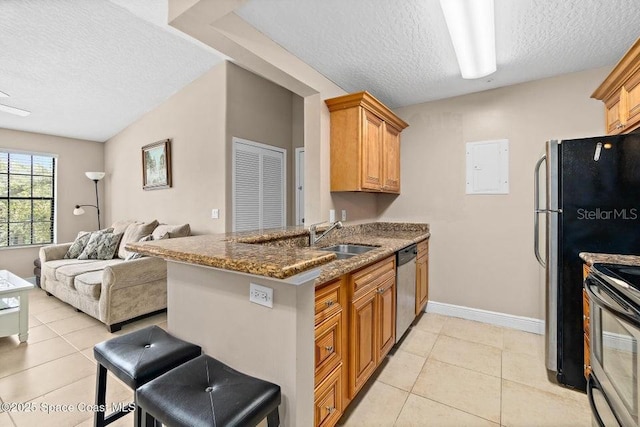 kitchen featuring light tile patterned floors, sink, kitchen peninsula, stainless steel appliances, and a breakfast bar area