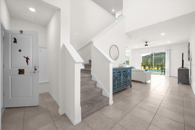 stairway featuring ceiling fan, tile patterned flooring, and a high ceiling