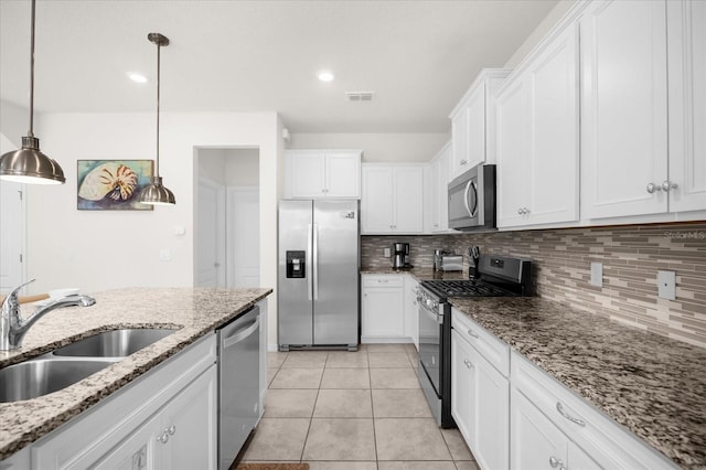 kitchen featuring decorative light fixtures, white cabinetry, sink, stainless steel appliances, and light stone countertops