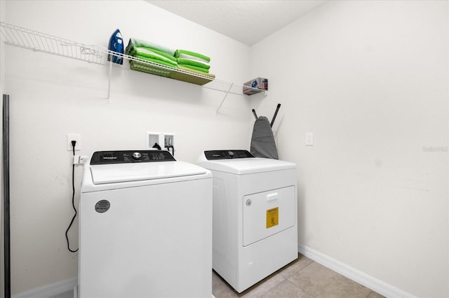 clothes washing area with light tile patterned flooring and separate washer and dryer