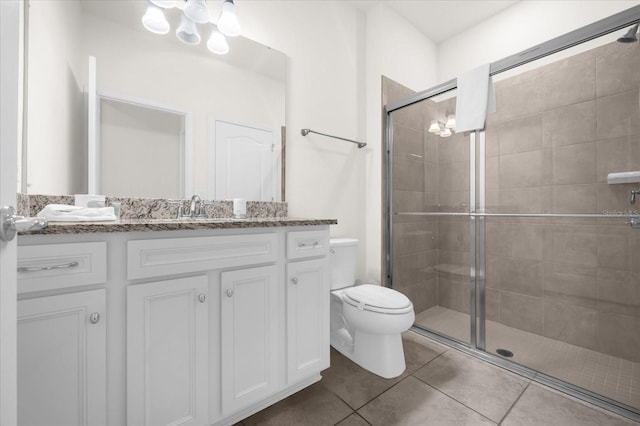 bathroom with tile patterned flooring, vanity, a shower with door, and toilet