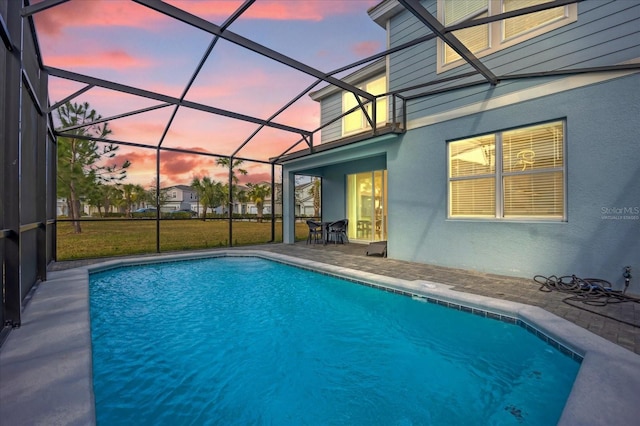 pool at dusk with a yard, a lanai, and a patio